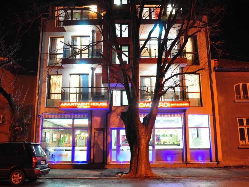 un edificio con un árbol delante de él en Lombardi Family Hotel en Ruse