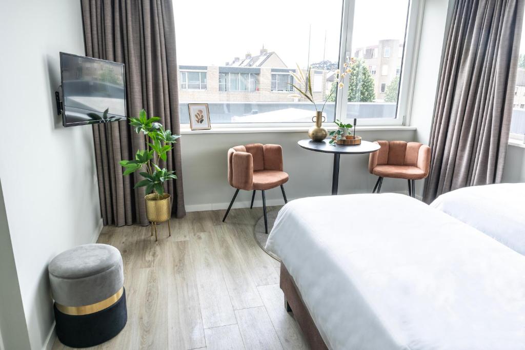 a hotel room with a bed and a table and a window at Renovated Suite With Kitchen Access And Bathroom in Raamsdonksveer