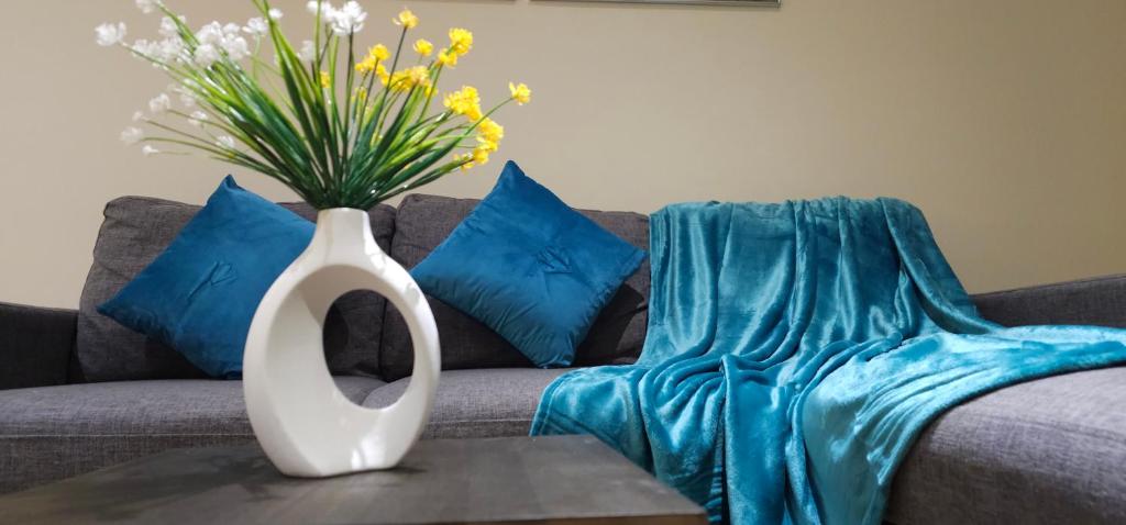 a vase with flowers on a table in front of a couch at Modern Apartment 5 at Christchurch Park in Ipswich