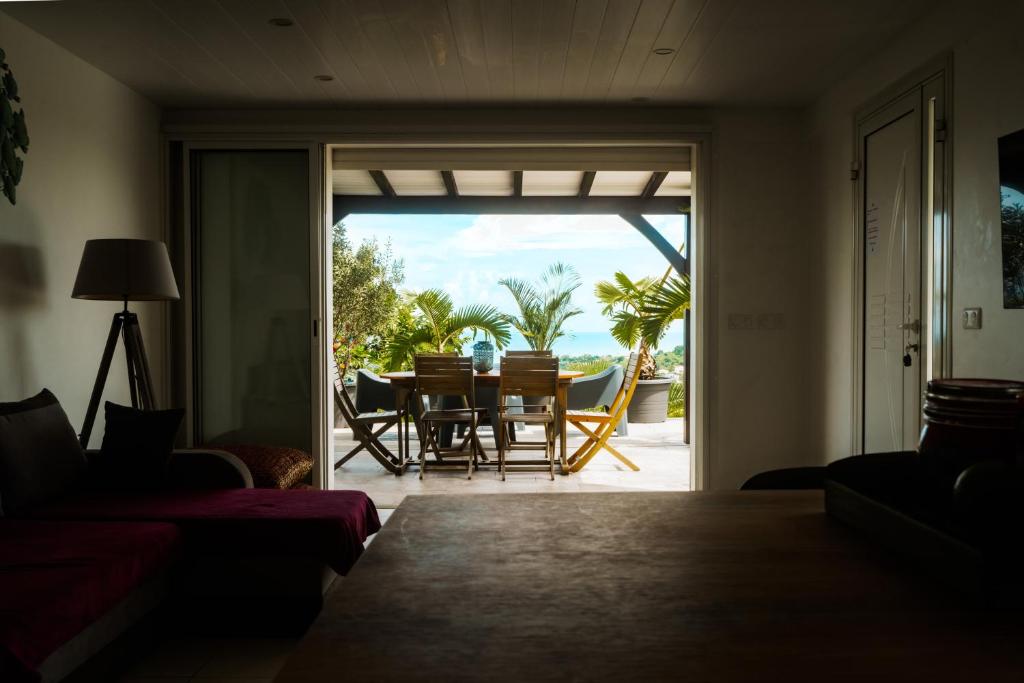un soggiorno con vista su un tavolo e sedie di Bas de villa le rêve éveillé a Le Robert