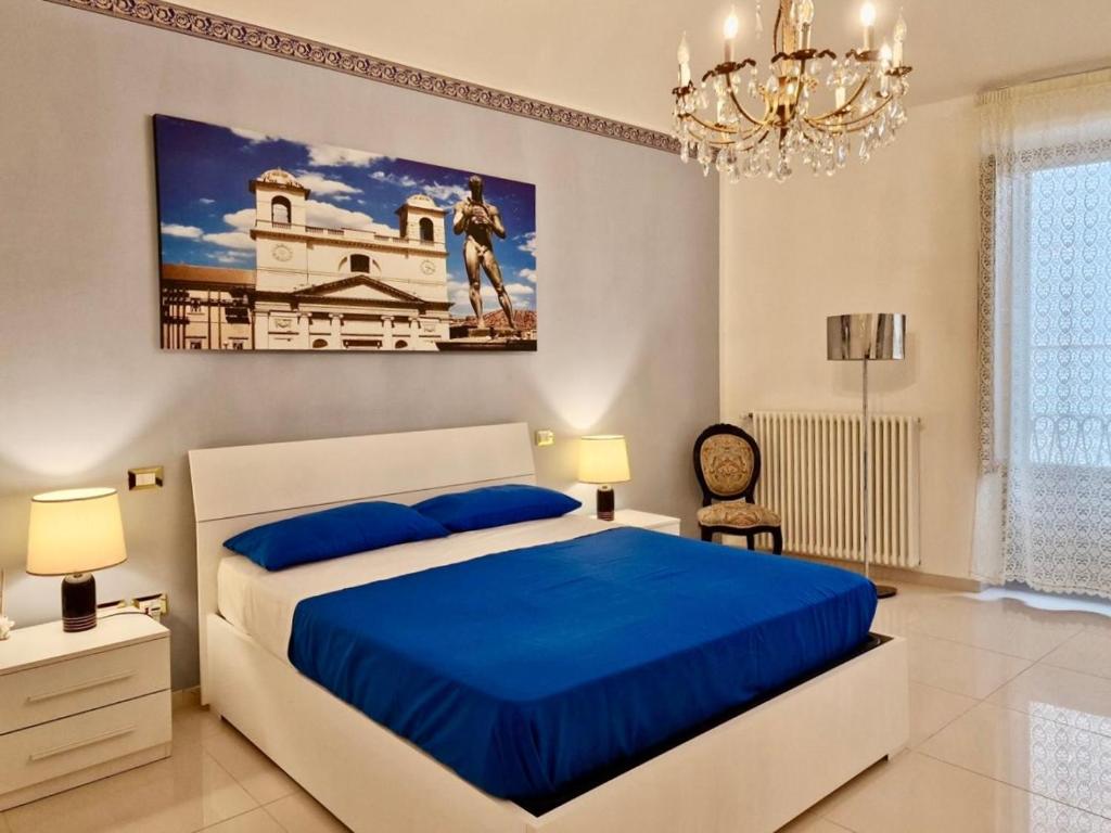 a bedroom with a bed with blue sheets and a chandelier at Anime Sante Apartment - Piazza Duomo in LʼAquila