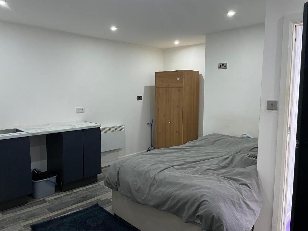 een witte kamer met een bed en een bureau bij Cosy studio in Queensbury