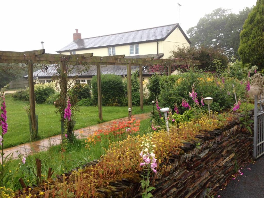 a garden with a pergola and flowers at Barton Gate Farm B&B in Bude