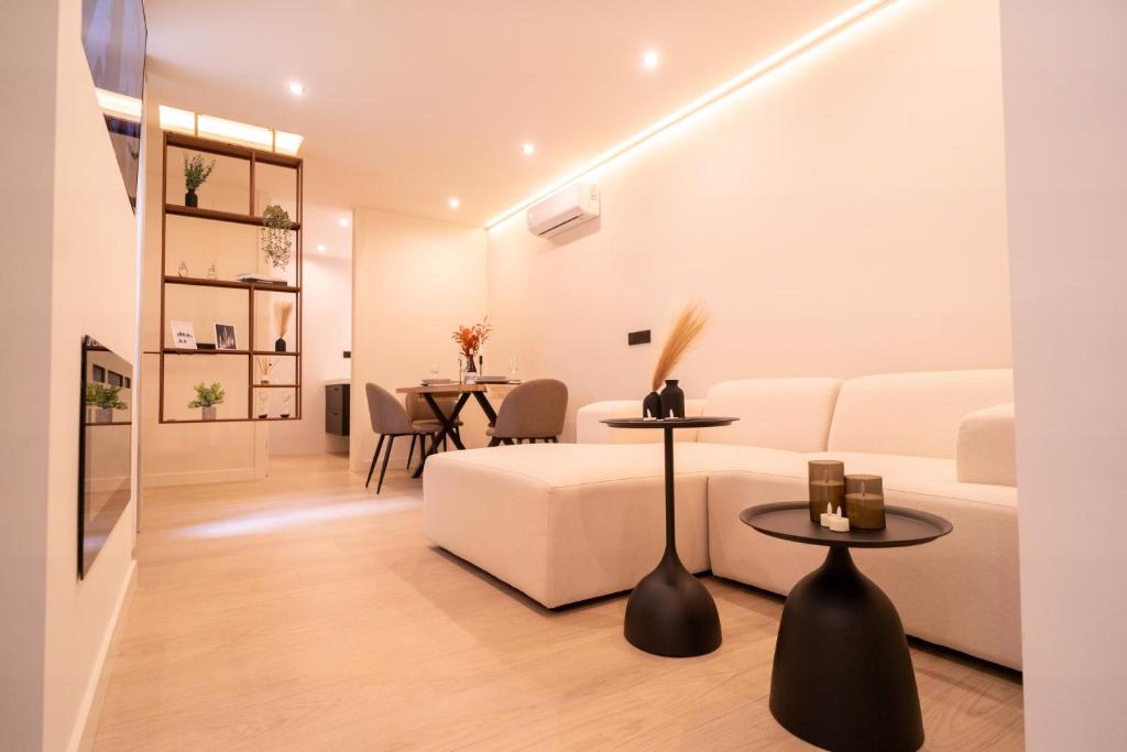 una sala de estar con un sofá blanco y mesas. en SERAN II Apartamentos, en Ronda