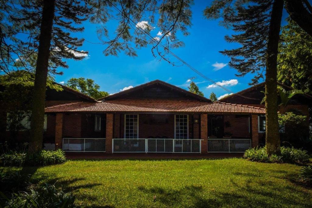 a house with trees in front of it at Rancho Ouro Verde Rolândia Pr in Rolândia