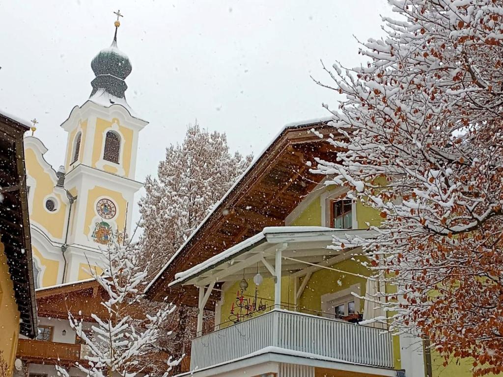 een gebouw met een toren en een kerk in de sneeuw bij Rosenberger I in Hopfgarten im Brixental