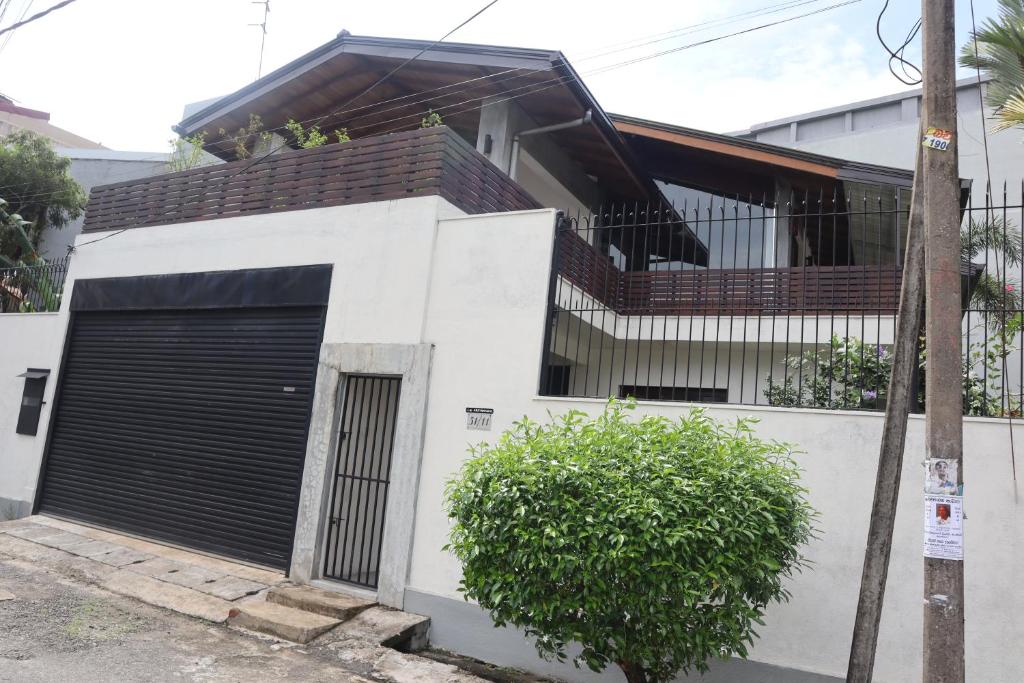 a white house with a gate and a garage at Mount Bliss Home Stay in Mount Lavinia