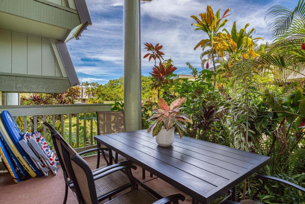 a wooden table and chairs on a porch with a plant at Puamana 26B in Princeville