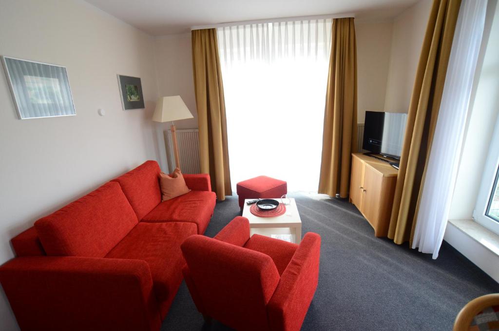 a living room with a red couch and two chairs at Ferienwohnung 2 im Haus Hühnergott Sellin in Ostseebad Sellin