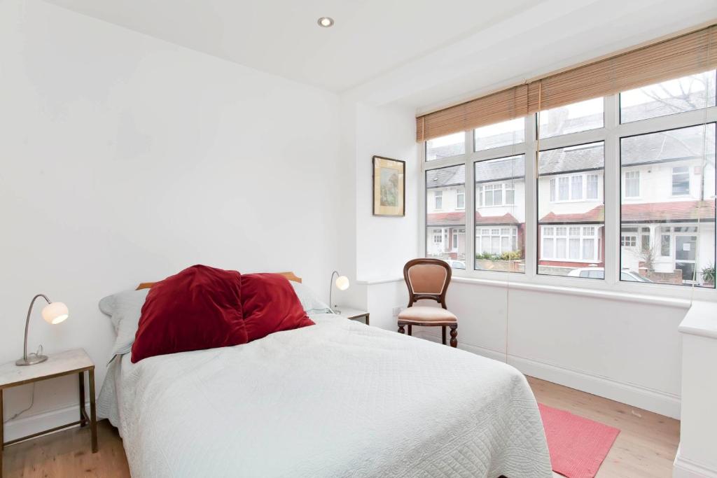 een witte slaapkamer met een bed en een raam bij Edencourt Apartment in Londen