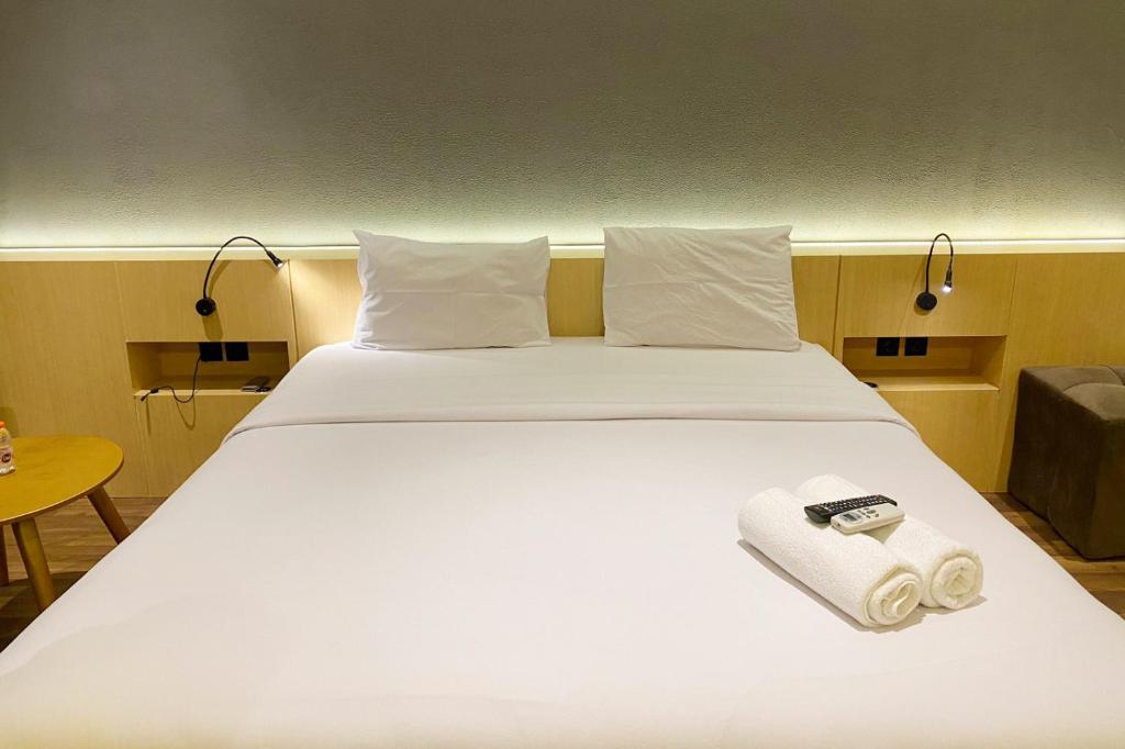 ein weißes Bett mit einer Kamera darüber in der Unterkunft Scenic and Homey Studio Mataram City Apartment By Travelio in Kejayan