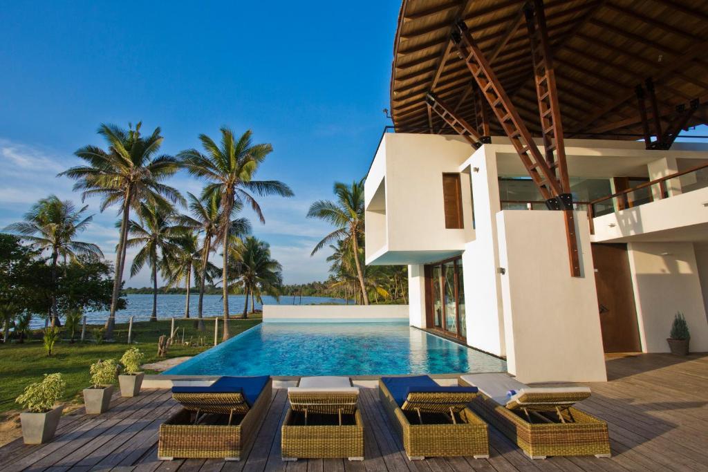 a villa with a swimming pool and palm trees at Villa Santé in Kalpitiya