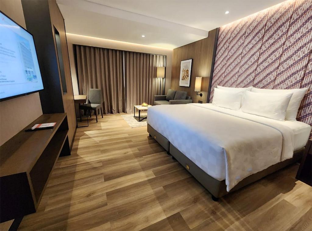 a hotel room with a bed and a flat screen tv at Swiss-Belhotel Airport Yogyakarta in Yogyakarta