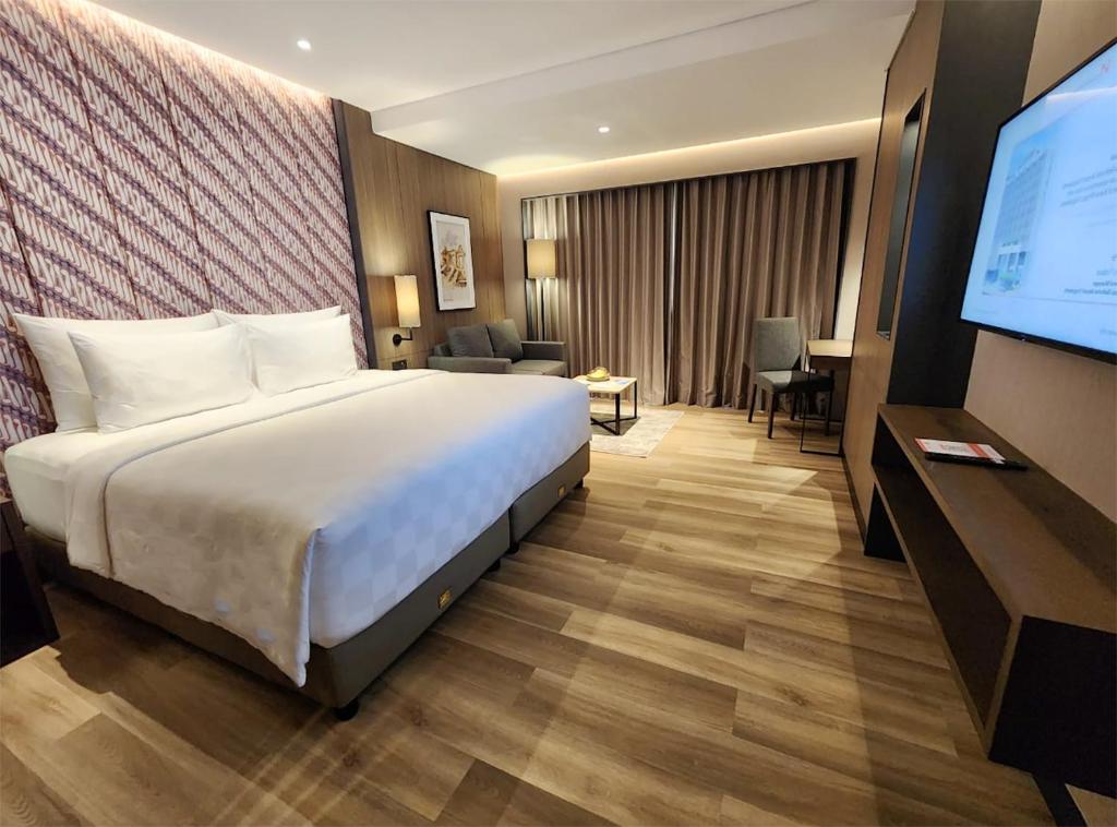 a hotel room with a bed and a flat screen tv at Swiss-Belhotel Airport Yogyakarta in Yogyakarta