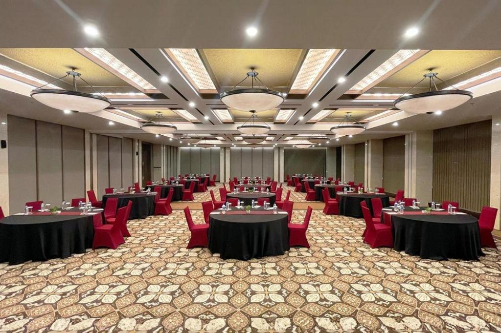 a large banquet hall with tables and red chairs at Swiss-Belhotel Airport Yogyakarta in Yogyakarta
