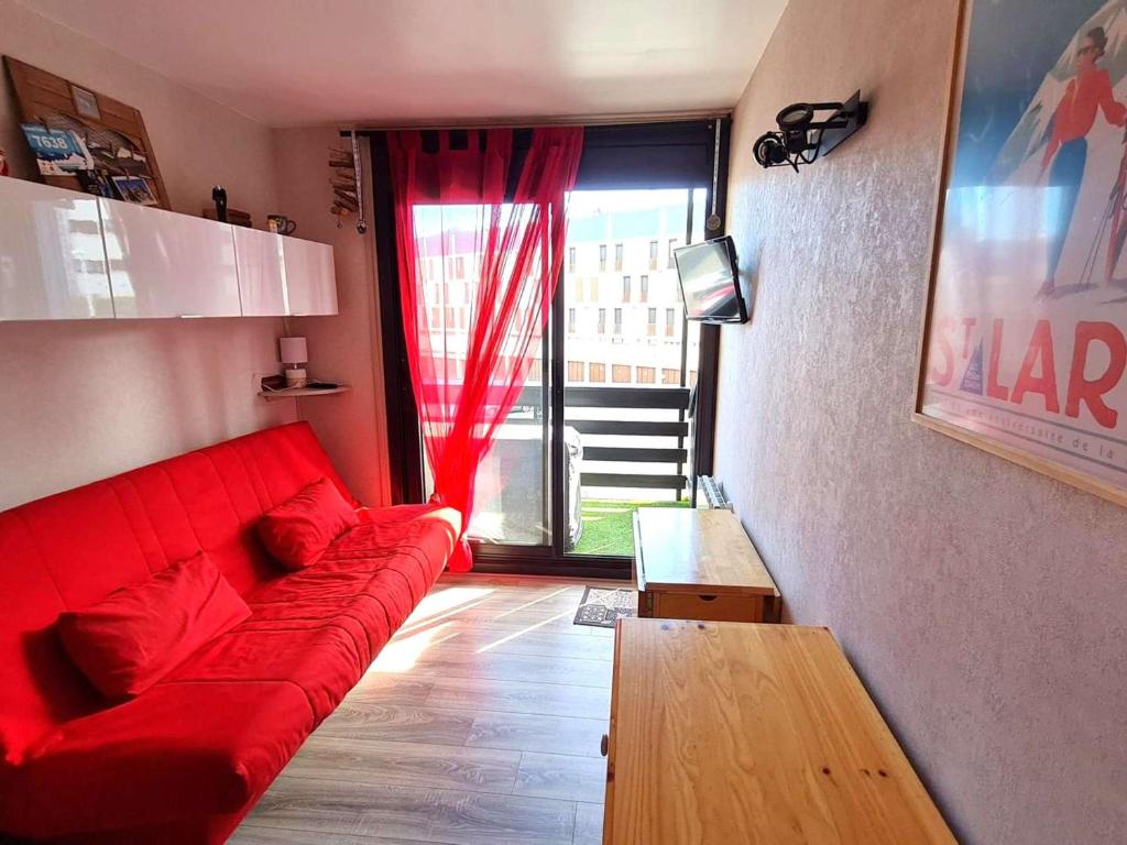 un canapé rouge dans un salon avec une fenêtre dans l'établissement Studio confortable 4 pers avec balcon au Pla d'Adet - FR-1-457-366, à Saint-Lary-Soulan