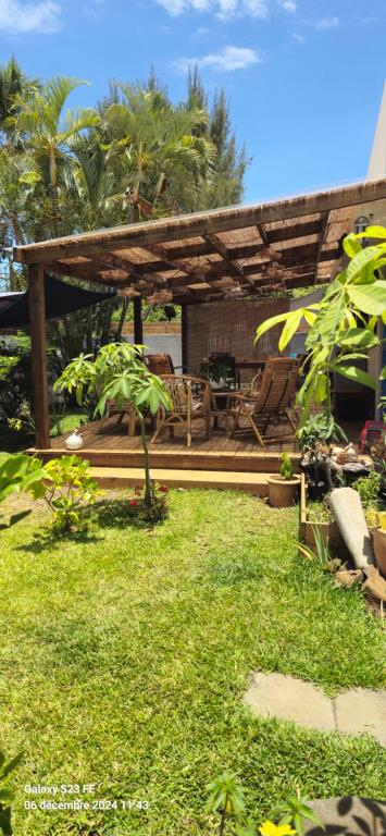a backyard with a wooden pergola and green grass at Ty kaz les bains in Saint-Paul
