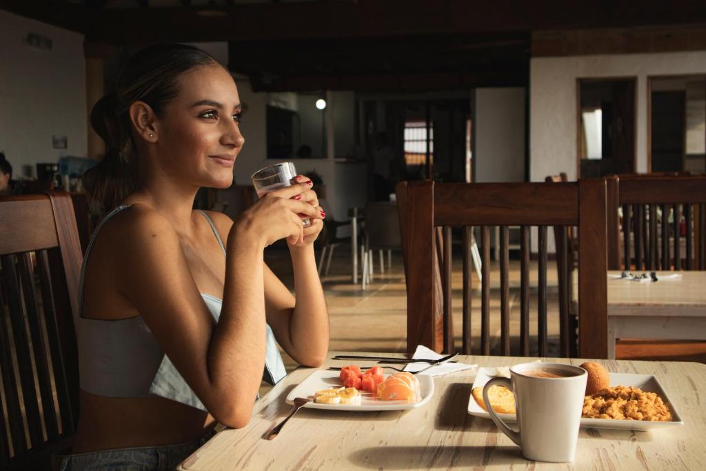a woman sitting at a table with a plate of food at Hotel Santa Laura Jerico in Jericó