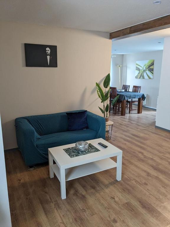 a living room with a blue couch and a table at Große Landhauswohnung in Ramhusen
