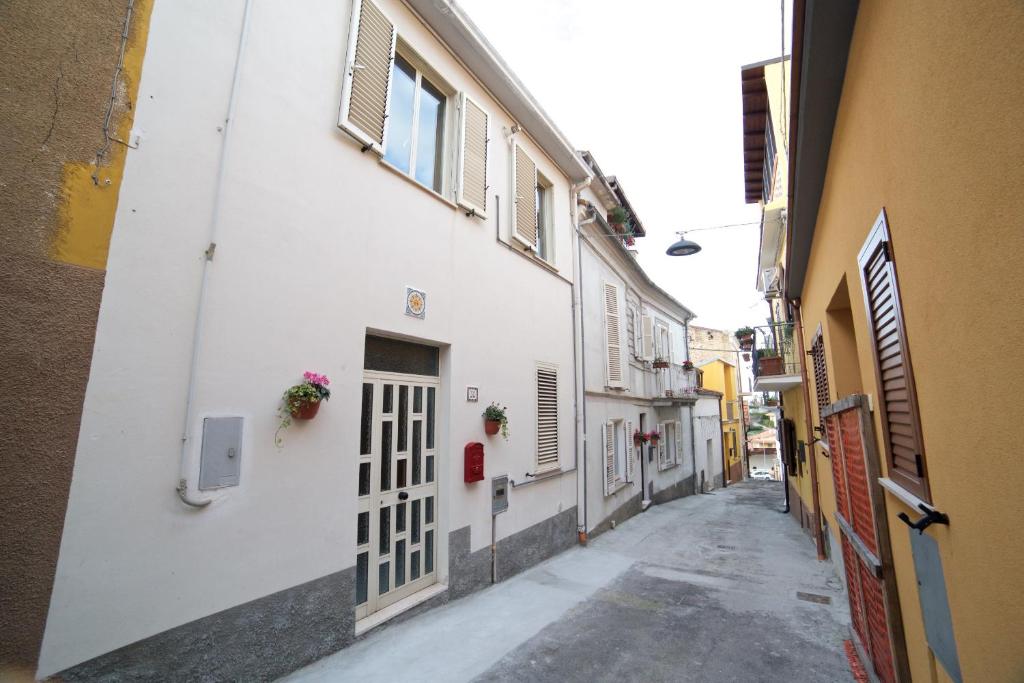 an alley with a white building with a gate and flowers at Casette Bianche in Casalbordino