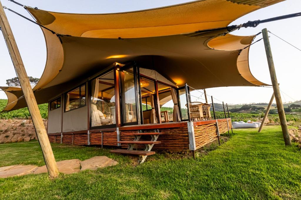 a house with a large roof on the grass at Amperbo Glamping in Cape Town