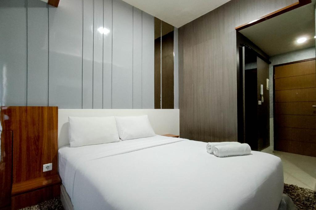 a large white bed in a room with a door at Relaxing Studio at Vida View Makassar Apartment By Travelio in Pampang