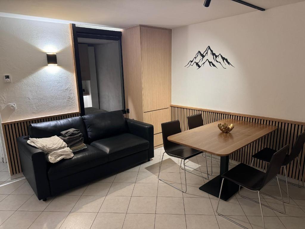 un salon avec un canapé noir et une table dans l'établissement Les 4 maisons Brides-les-Bains, à Brides-les-Bains