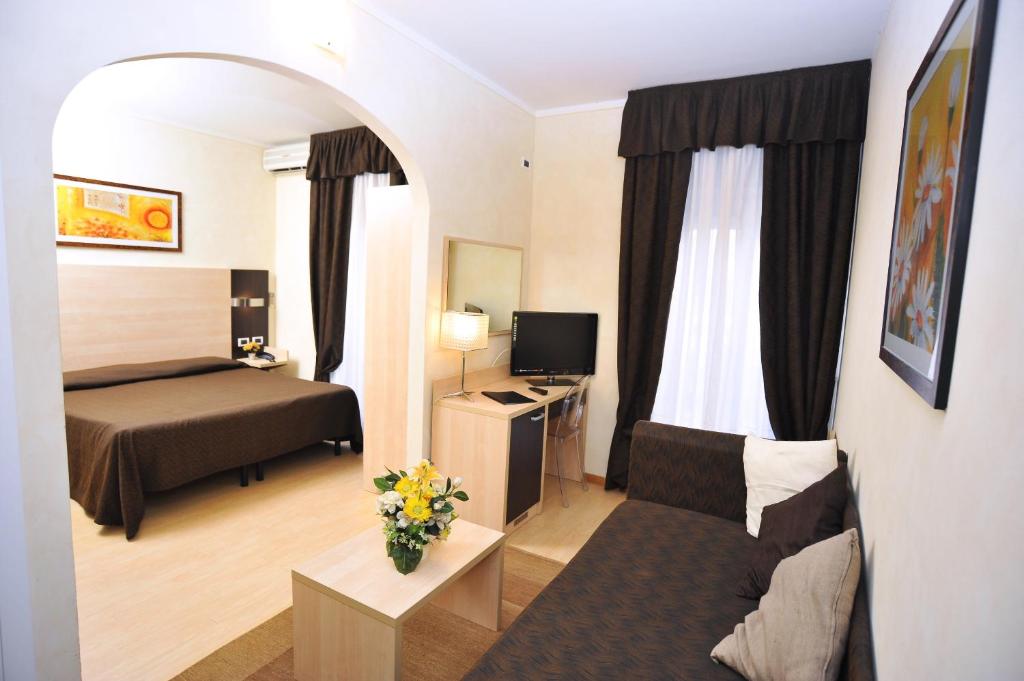 モンテカティーニ・テルメにあるホテル マッシモ ダツェリオのベッドとソファ付きの小さなホテルルーム