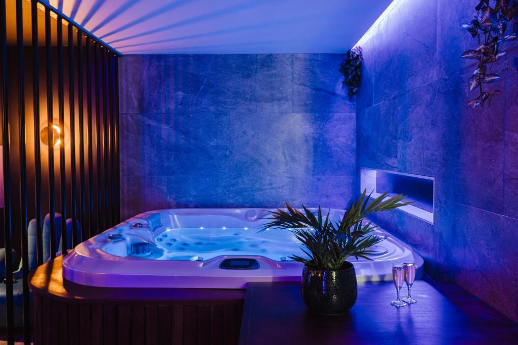 une salle de bains bleue pourvue d'une baignoire avec une plante en pot dans l'établissement Love Room Les Private Places - Lit King Size et Jacuzzi Privé, à Orléans