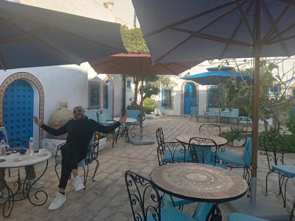 a man is dancing in a patio with tables and chairs at Hôtel Bou Fares in Sidi Bou Saïd