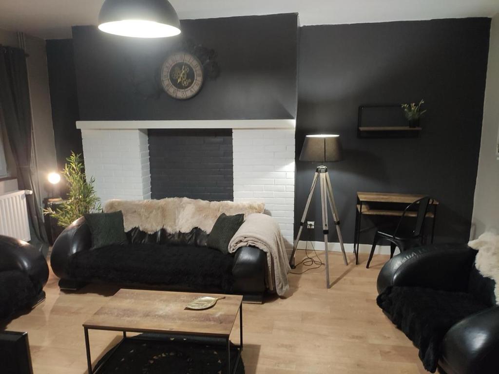 a living room with a black couch and a fireplace at Maison de ville in Bourbourg
