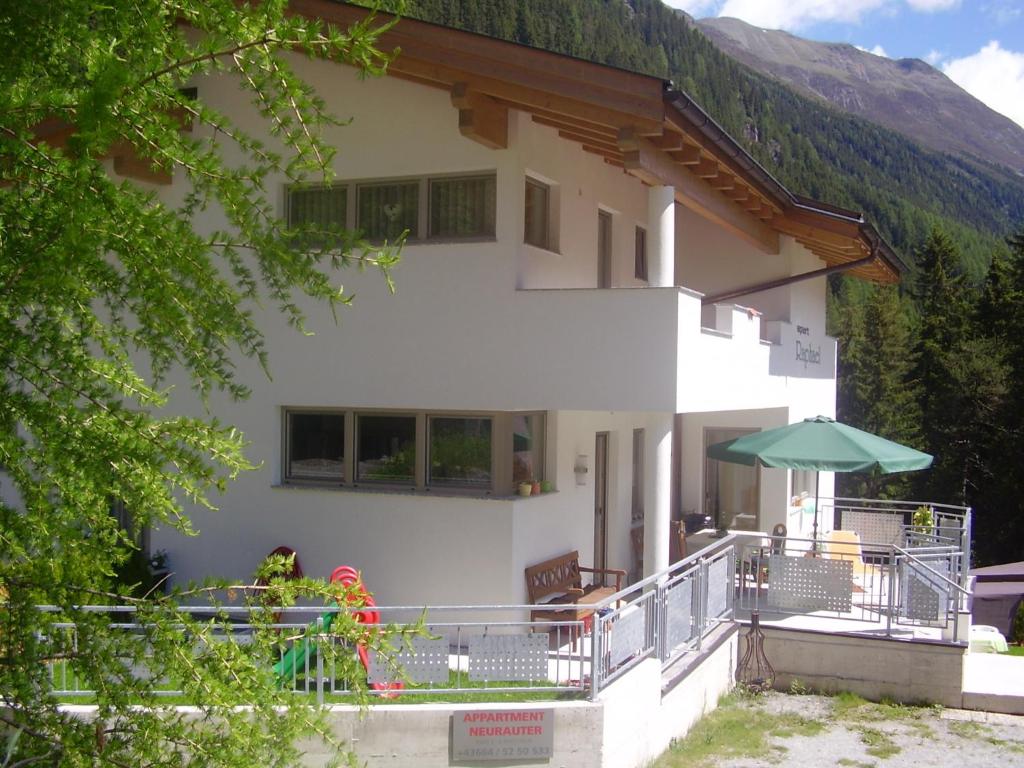 a white house with an umbrella in front of it at Apart Raphael in Niederthai