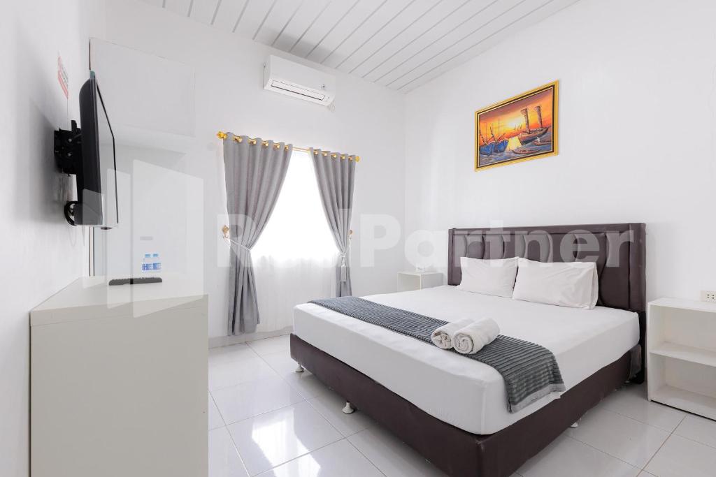 une chambre blanche avec un lit et une télévision dans l'établissement Sanama Kostel 2 Syariah Lampung RedPartner, à Lampung