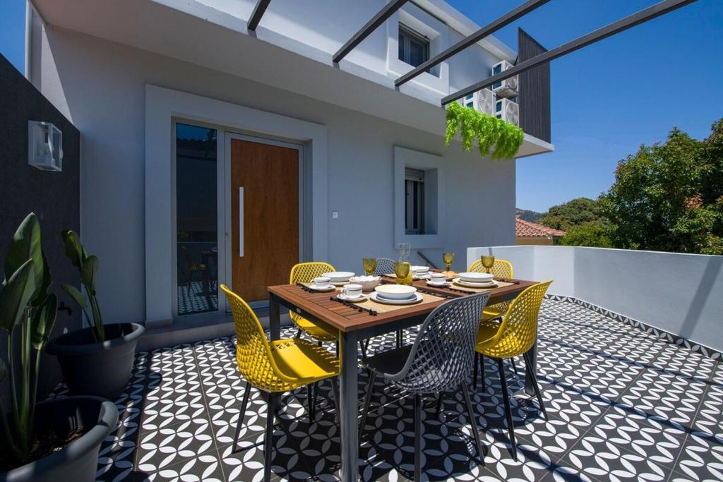 a patio with a wooden table and yellow chairs at Casa Di Camomilla in countryside in Chania Town