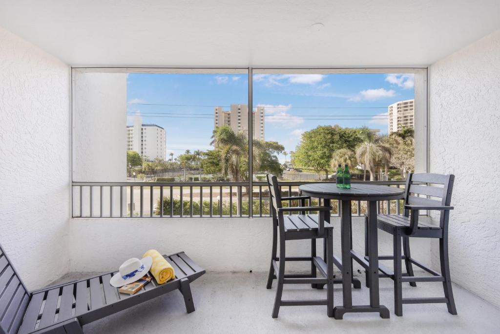 a balcony with a table and chairs and a window at Relaxing inland condo with pool and steps to beach in Marco Island