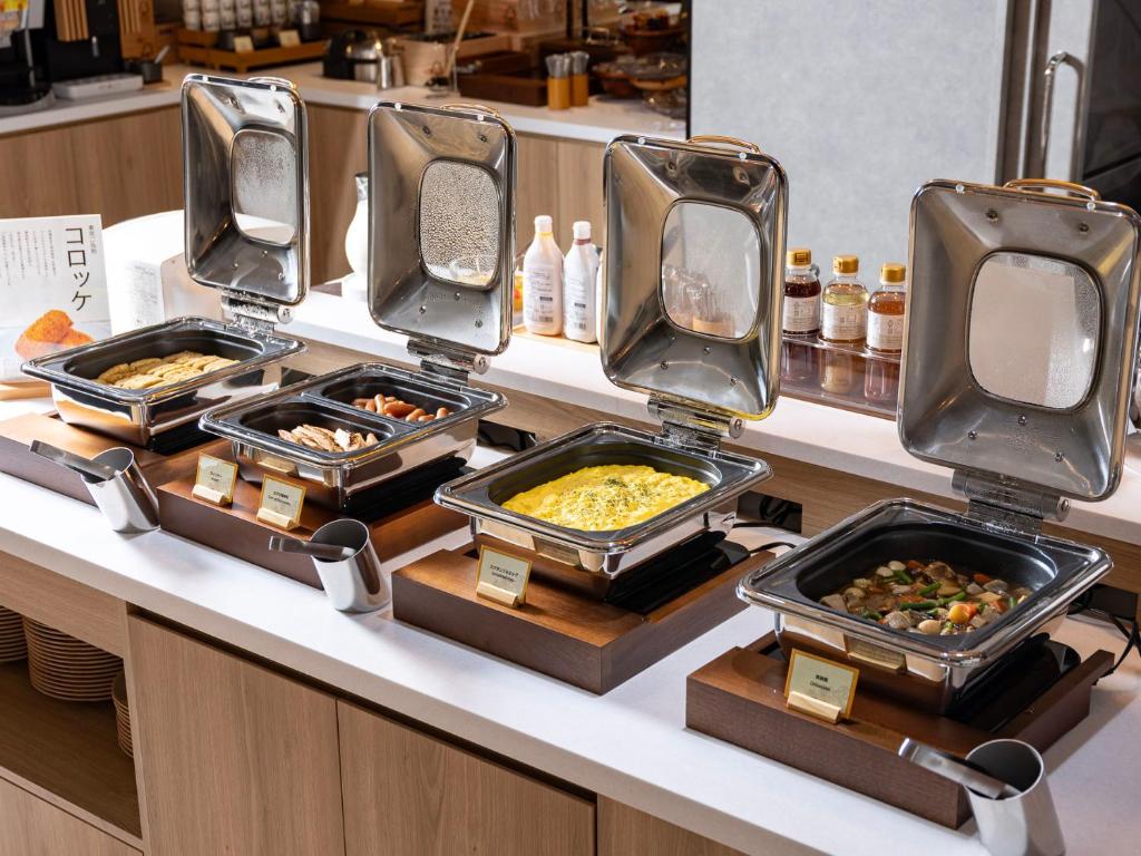 a buffet with several trays of food on a counter at SUPER HOTEL Ikebukuro West Natural Hot Spring in Tokyo