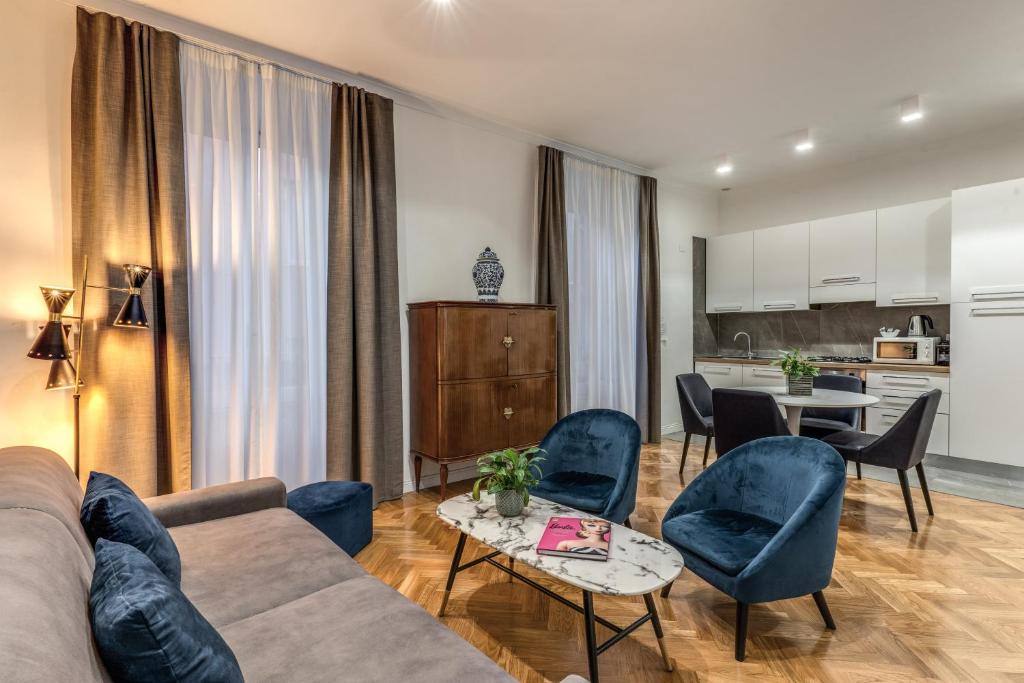 Una sala de estar con un sofá y sillas y una cocina. en Margana Apartment - Maison D'art Collection, en Roma