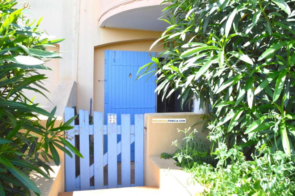 une porte bleue devant un bâtiment avec des plantes dans l'établissement NP340-P27 Appartement studio, Narbonne Plage, à Narbonne-Plage