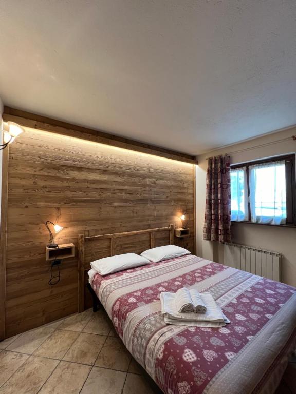 a bedroom with a bed with a wooden wall at Baita Arianna BILOCALE FRAITEVE in Sestriere