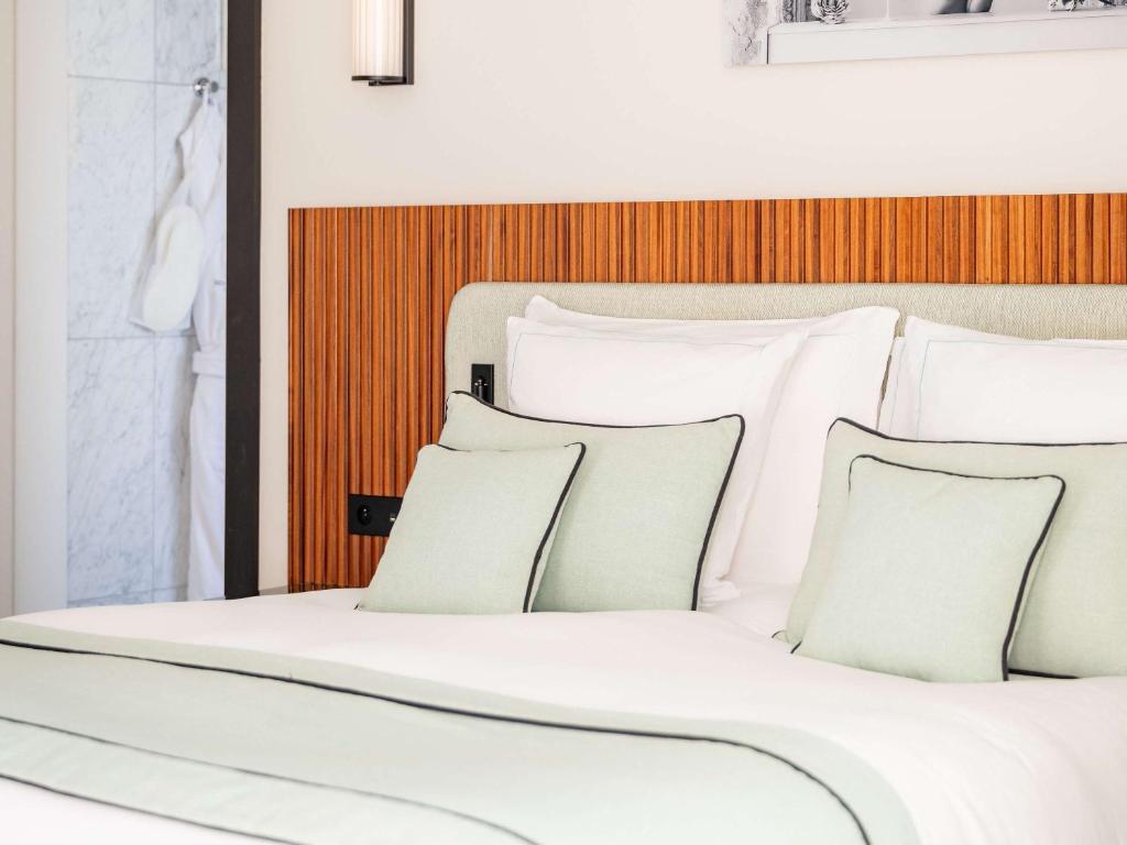a bed with white sheets and pillows at Mondrian Cannes in Cannes