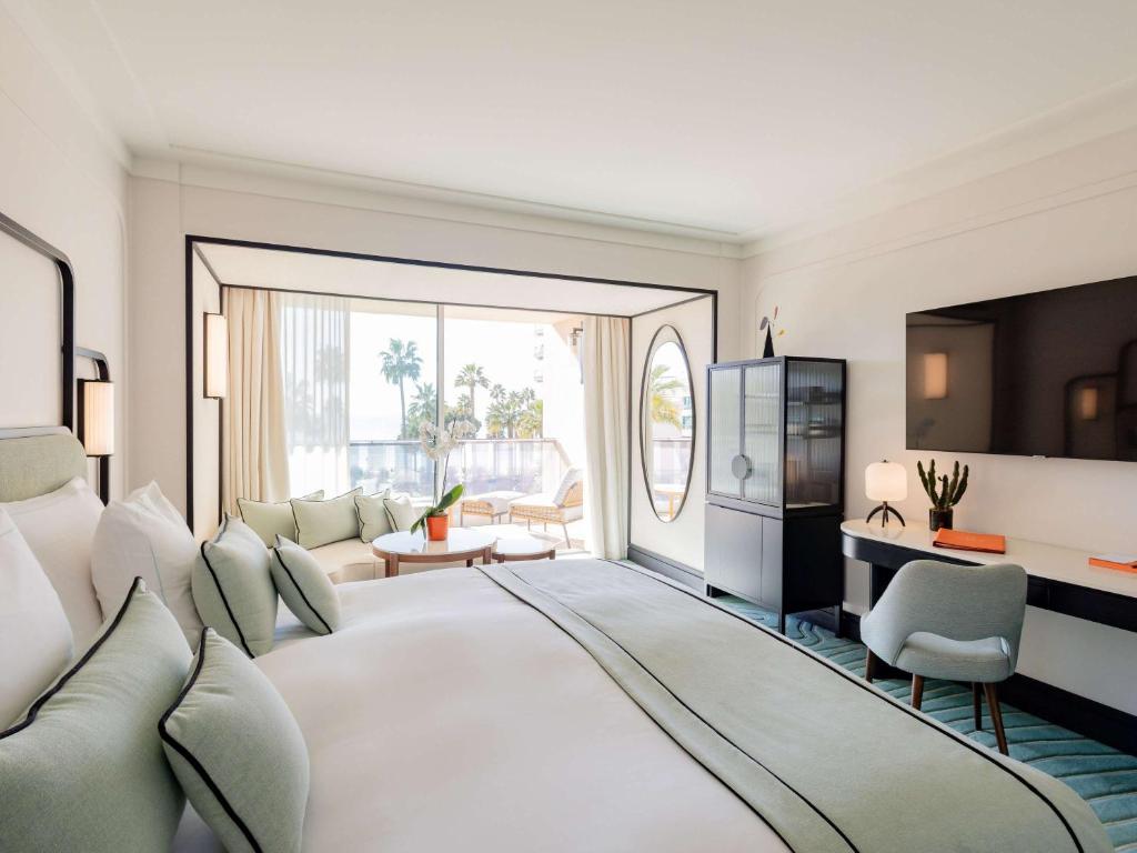 a bedroom with a large white bed and a living room at Mondrian Cannes in Cannes