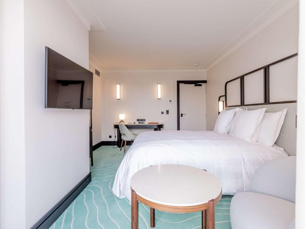 a hotel room with a large bed and a table at Mondrian Cannes in Cannes