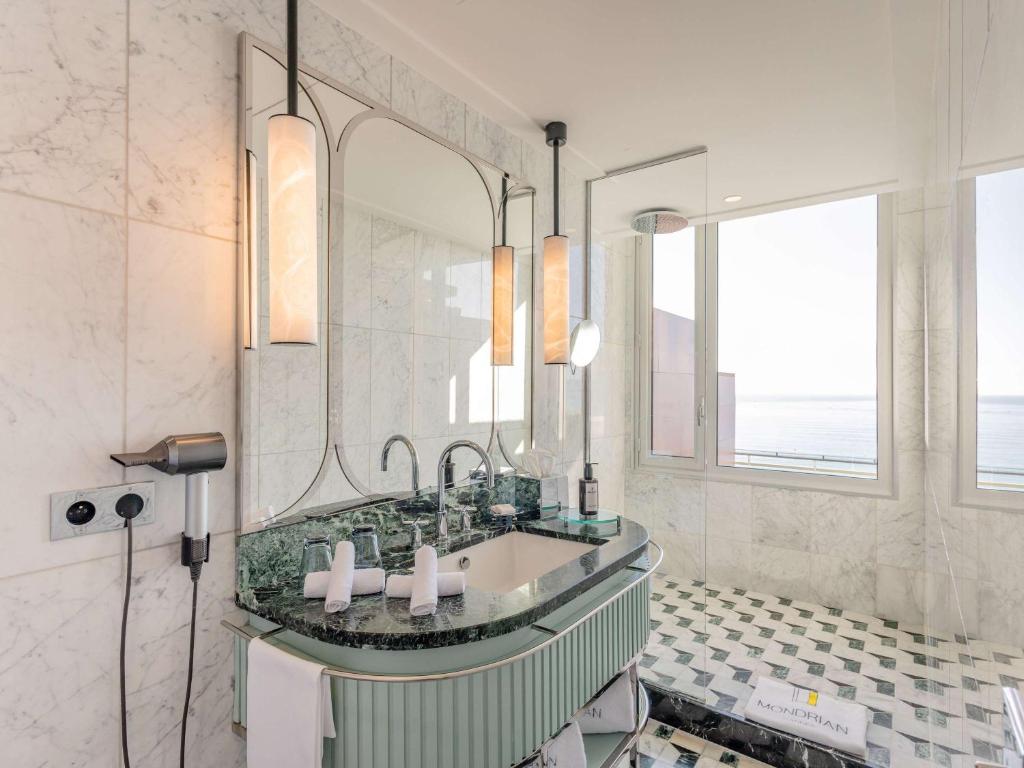 a bathroom with a sink and a large mirror at Mondrian Cannes in Cannes