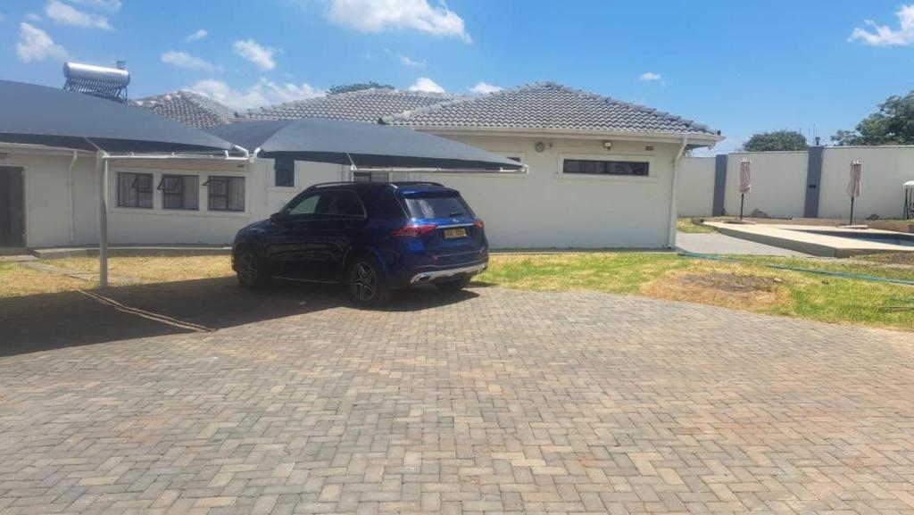 a car parked in front of a house with an umbrella at Gletwyn House Retreat in Harare in Helensvale