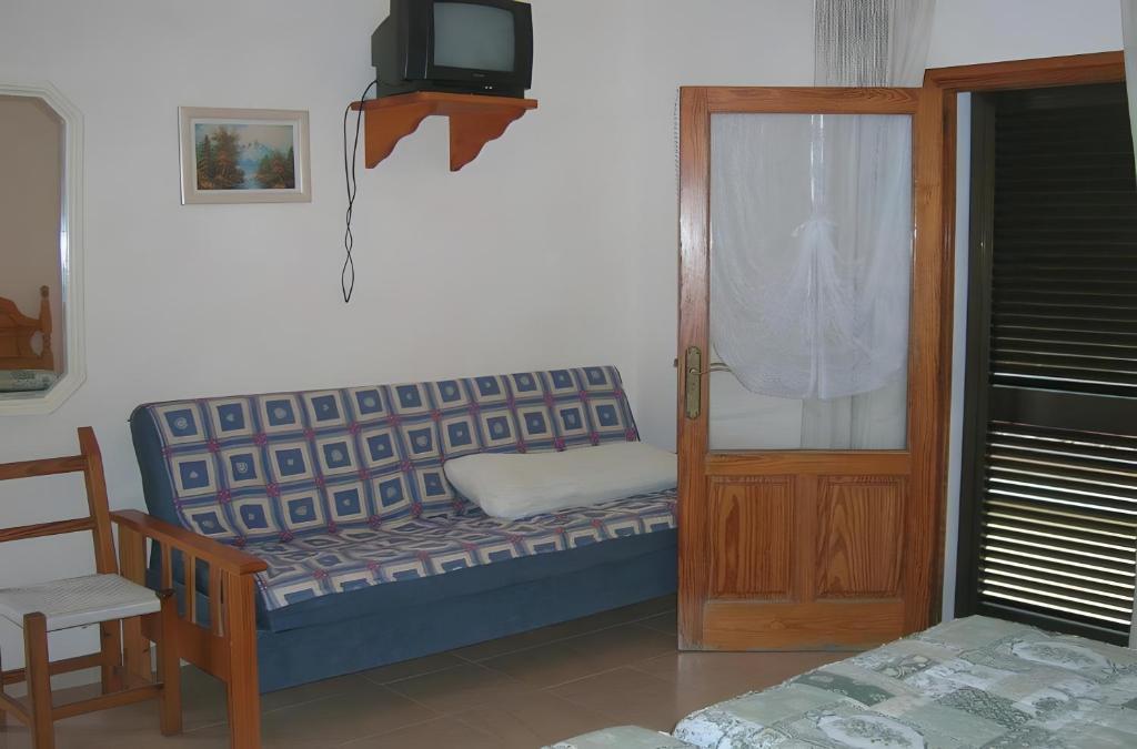 a room with a bench and a tv and a door at Pensión las 3 Golondrinas in Santa Eularia des Riu