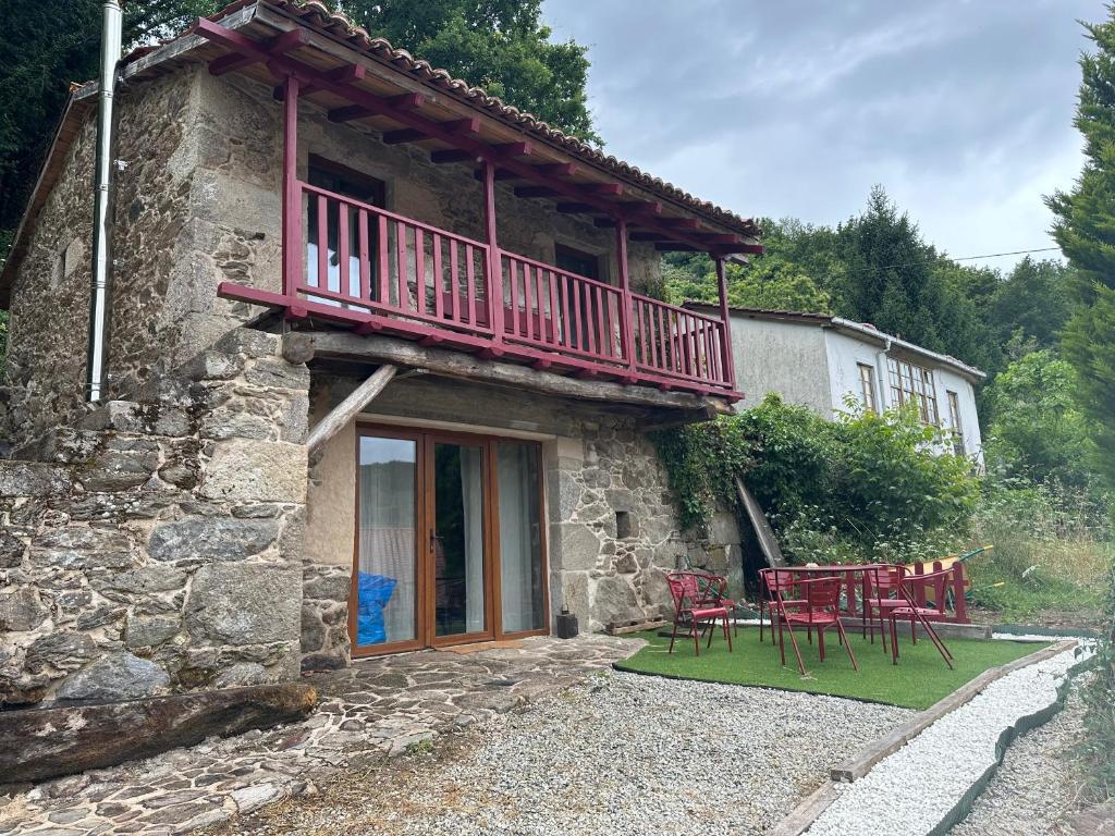 a building with a balcony and red tables and chairs at Lagar de Guxeva in Chantada