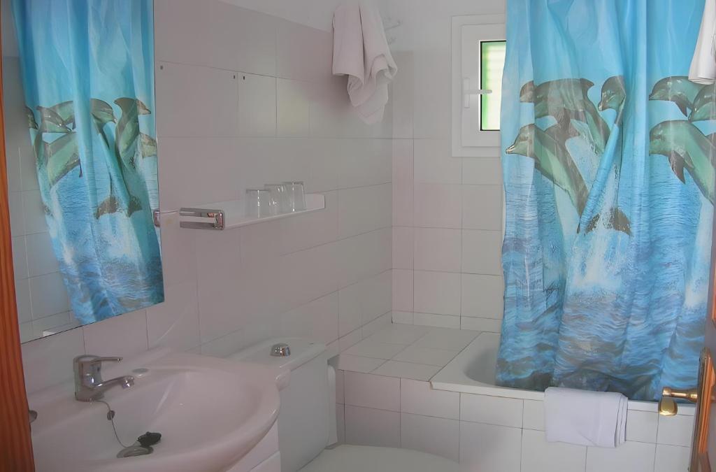 a bathroom with a sink and a shower curtain at Pensión las 3 Golondrinas in Santa Eularia des Riu