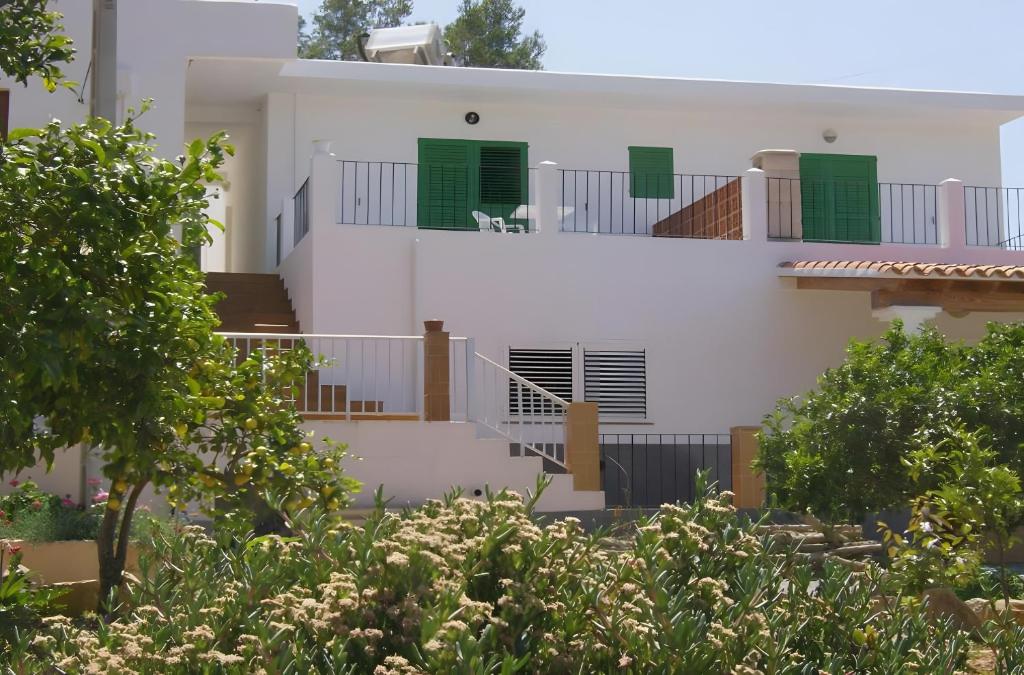 a white house with green doors and a balcony at Pensión las 3 Golondrinas in Santa Eularia des Riu