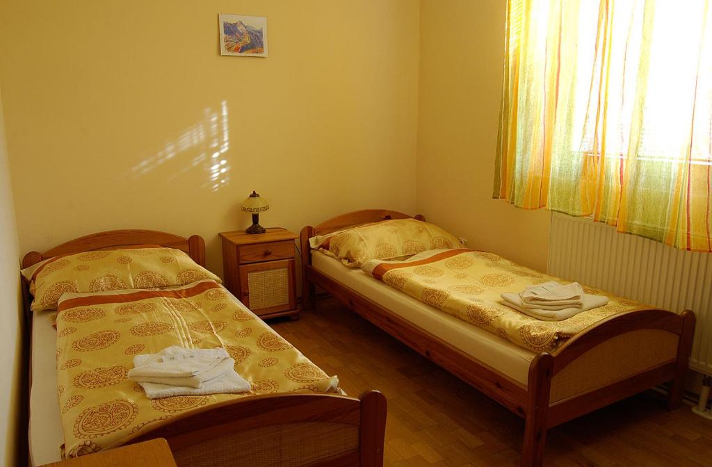 two beds in a small bedroom with a window at Penzion Majak in Banská Bystrica