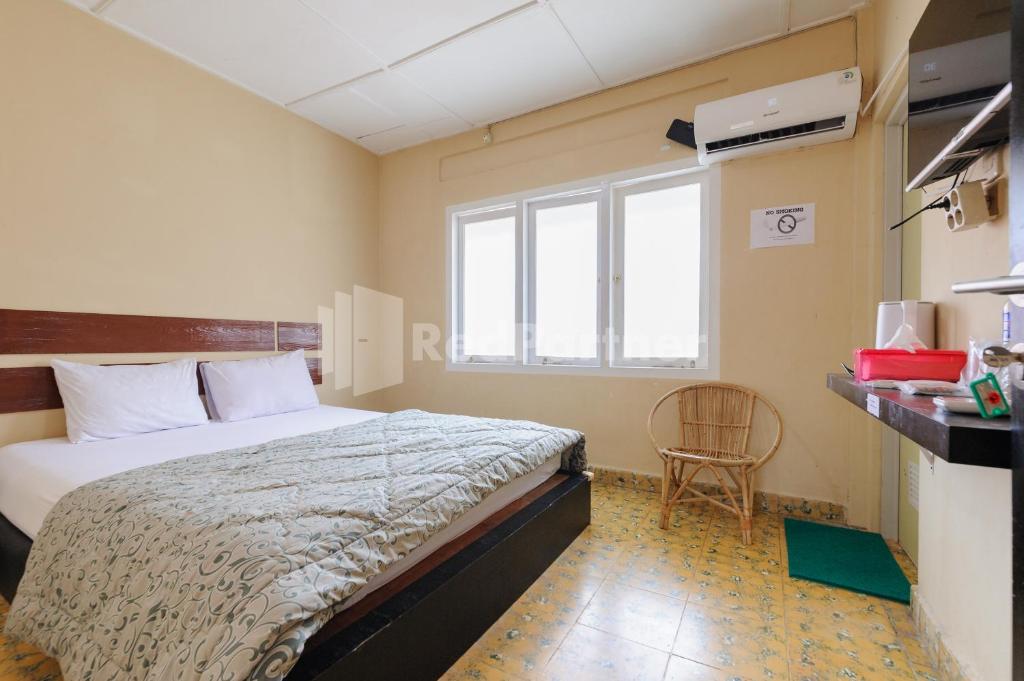 een slaapkamer met een bed en een stoel erin bij Arwana Inn Syariah Lampung Mitra RedDoorz in Bandar Lampung